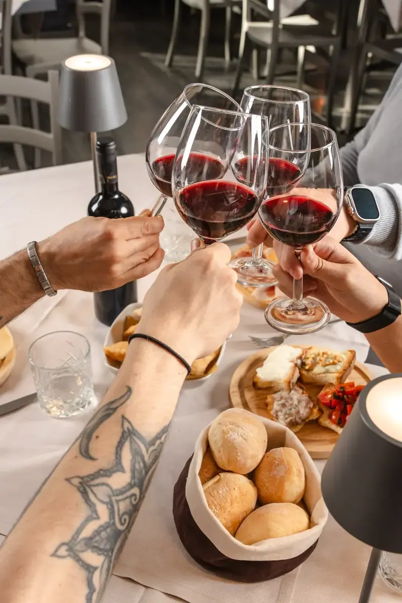 Mani che alzano i calici sopra la tavola