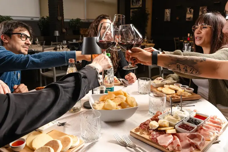 Amici che brindano sorridendo sopra i taglieri