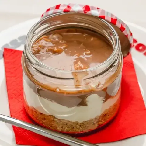 Cheesecake del Momento nel barattolo di vetro, sul piattino con il tovagliolo rosso