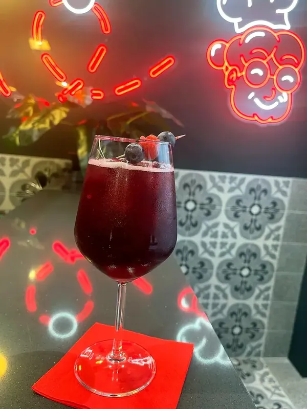 Un cocktail rosso nel calice, sul tovagliolo rosso del bancone