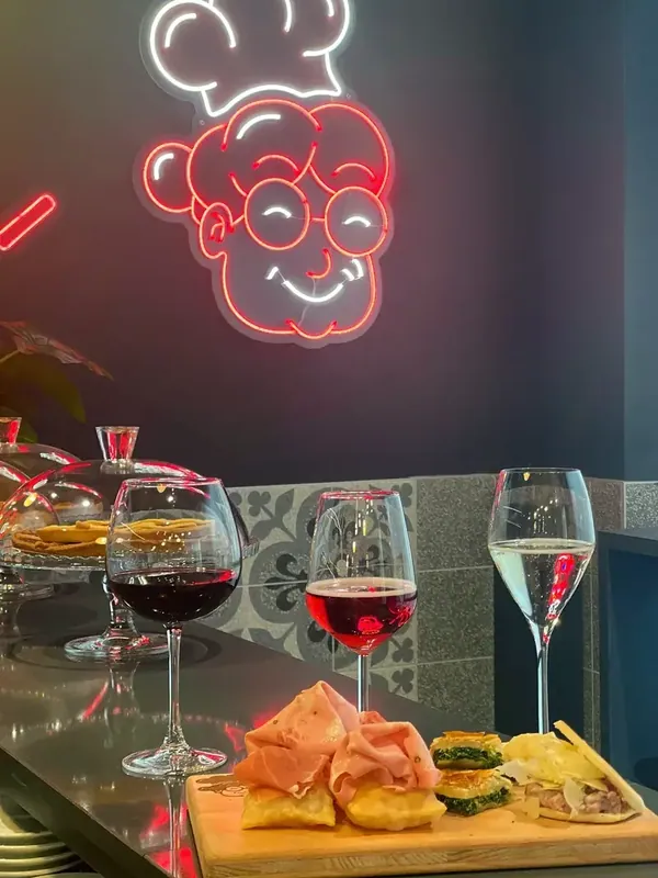 Three glasses and a board of tigelle under Nonna’s neon sign