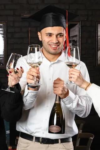 Un ragazzo festeggia la laurea brindando con gli amici