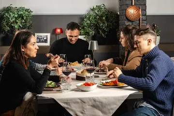 Una tavolata di amici a cena, tra piatti e bicchieri