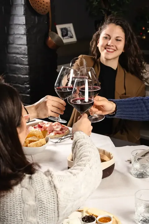 Una ragazza sorride alzando il calice a tavola