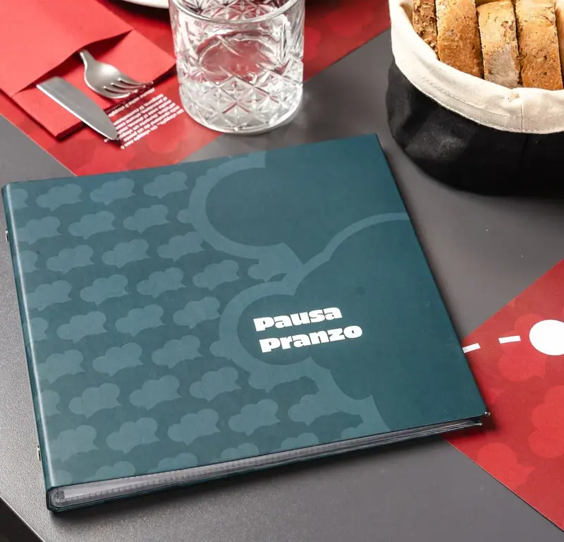 Il menù della pausa pranzo sul tavolo, accanto al cestino del pane e a un bicchiere d’acqua