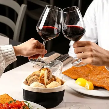Due calici di rosso alzati per un brindisi a tavola